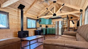 A cozy cabin interior with a wooden interior, a sofa, a table, and a kitchen area.