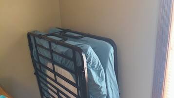Een hoek kamer met een stapelbed, een houten dressoir en een lijst met een foto aan de muur.