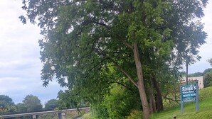A riverside area with a bridge, a sign for Sivak's Vacation Rental Private Dock, and lush greenery.