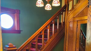 A wooden staircase with red carpeted steps and a wooden handrail.
