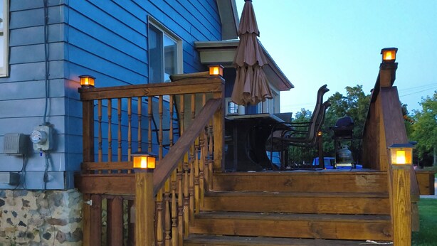A wooden staircase leading to a porch with a table and umbrella.