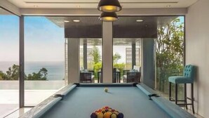 A pool table with balls, a bar area, and a view of the ocean. - Villa Samira | Kamala Sea View 6BR Villa | Pool, Chef, Spa (Kamala)