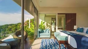 A modern hotel room with a large bed, a seating area with a sofa and armchairs, and a balcony with a view of the greenery. - Villa Samira | Kamala Sea View 6BR Villa | Pool, Chef, Spa (Kamala)