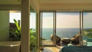 A modern bedroom with a large sliding glass door leading to a balcony with a city view. - Villa Samira | Kamala Sea View 6BR Villa | Pool, Chef, Spa (Kamala)