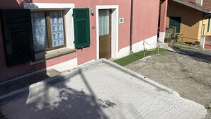 A building with a pink facade, green shutters, and a small entrance. - Apartment with sea view relaxation and peace (MONEGLIA)