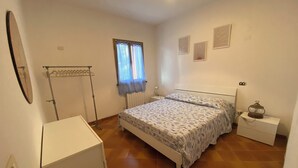 A bedroom with a bed, a radiator, a window with curtains, a bedside table with a lamp, and a wardrobe. - Apartment with sea view relaxation and peace (MONEGLIA)