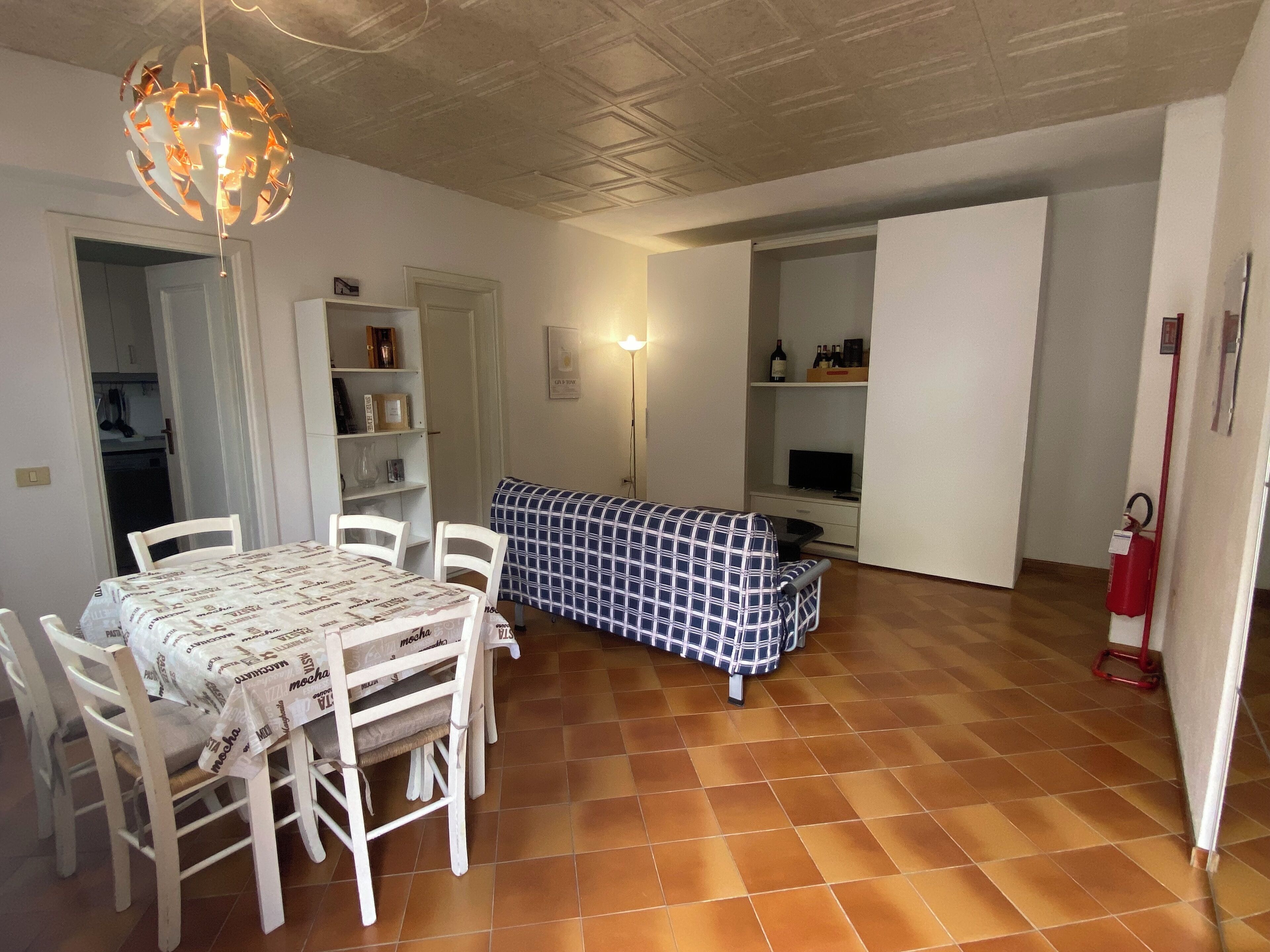 Ein Essbereich mit Tisch und Stühlen, einer Couch und einem Fernseher.