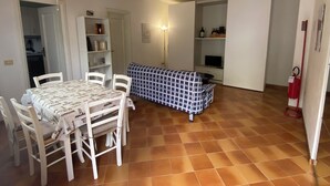 A dining area with a table and chairs, a sofa, and a television. - Apartment with sea view relaxation and peace (MONEGLIA)