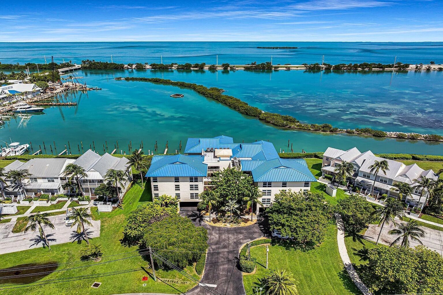 A coastal resort with multiple buildings, a marina, and clear blue waters.