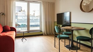 Una sala de estar moderna con un sofá, sillas, una mesa de comedor y un amplio ventanal con cortinas.