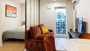 Una sala de estar moderna con sofá, cama, mesa de comedor y un balcón con vistas.