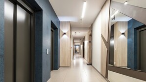 Een moderne hotelgang met een lange, rechte indeling, met een combinatie van donkere en lichte wanden en een betegelde vloer.
