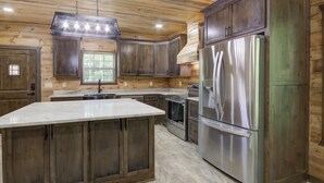 A kitchen with wooden cabinets, a stainless steel refrigerator, and a marble countertop.