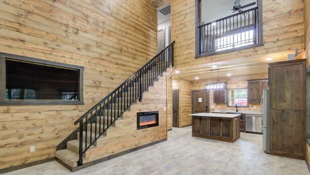 A spacious interior with a wooden staircase, a kitchen area, and a large window.