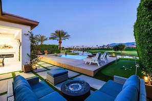 A poolside area with lounge chairs, a hot tub, and a view of a golf course.