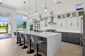 A modern kitchen with a large island, bar stools, and a view of the outdoors.