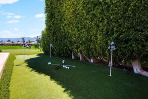 A well-manicured golf course with a putting green, a flagstick, and a golf ball.
