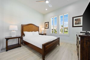 A bedroom with a wooden bed, nightstands, a ceiling fan, and a view through the window.