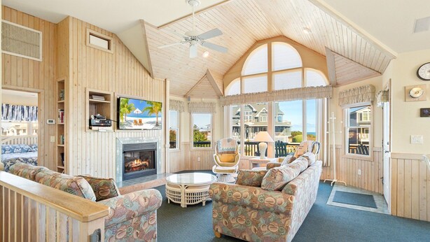 Una sala de estar acogedora con chimenea, asientos cómodos y grandes ventanales con vistas al exterior.