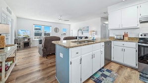 A modern kitchen with white cabinets, a granite countertop, and a built-in oven. - 200 Steps To Beach, Balcony Gulf Views, Firepit, Dog Friendly, 3BR Beach Home (Gulf Shores)