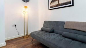 A modern living room with a grey sofa, a floor lamp, and a framed picture on the wall.