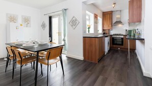 A modern kitchen with wooden cabinets, a built-in oven, and a dining area with a table and chairs.