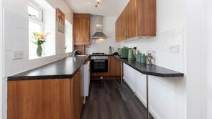 A kitchen with wooden cabinets, a black countertop, a stove, and a window with flowers.