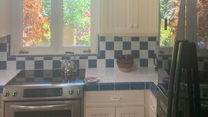 A kitchen with a checkered backsplash, a window with a view of trees, a kettle, and a stove. - Heidi's Artistic Abode, peaceful relaxation! (Three Rivers)