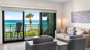 Ein modernes Wohnzimmer mit einem großen Schiebeglastür, die auf einen Balkon mit Meerblick führt.