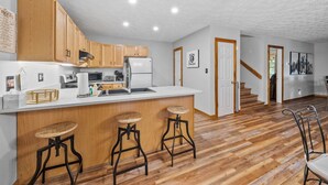 Une cuisine moderne avec des meubles en bois, un plan de travail blanc et un îlot central intégré, doté de tabourets.