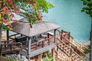 Eine Holzterrasse mit einem Gazebo, Sitzgelegenheiten im Freien und Blick auf einen See.