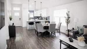 A modern kitchen with a central island, a dining area with a round table and chairs, and a living area with a sofa and a coffee table. - Family Getaway ~Renovated 3BR Home+ Private Pool Close to Airport, DT, & F1 (Austin)