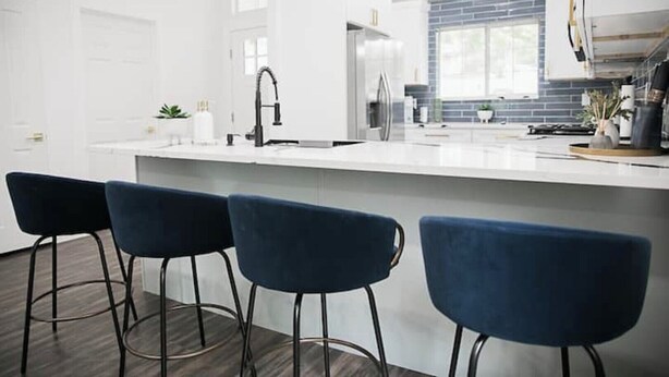 A modern kitchen with a large island, bar stools, and a backsplash. - Family Getaway ~Renovated 3BR Home+ Private Pool Close to Airport, DT, & F1 (Austin)