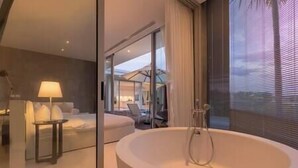 A modern bathroom with a large bathtub, a glass shower enclosure, and a view of the outdoor area.