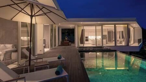 A modern house with a glass-enclosed swimming pool and a deck with outdoor furniture.