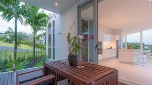 A modern kitchen with white cabinets and a large window overlooking a garden.