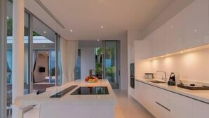A modern kitchen with a central island, large windows, and a minimalist design.