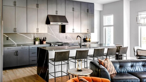 A modern kitchen with grey cabinets, a stainless steel range hood, and a central island with bar stools. - Rooftop w/ Skyline Views & Outdoor Kitchen-15 Min to Broadway-Family Friendly (Nashville)