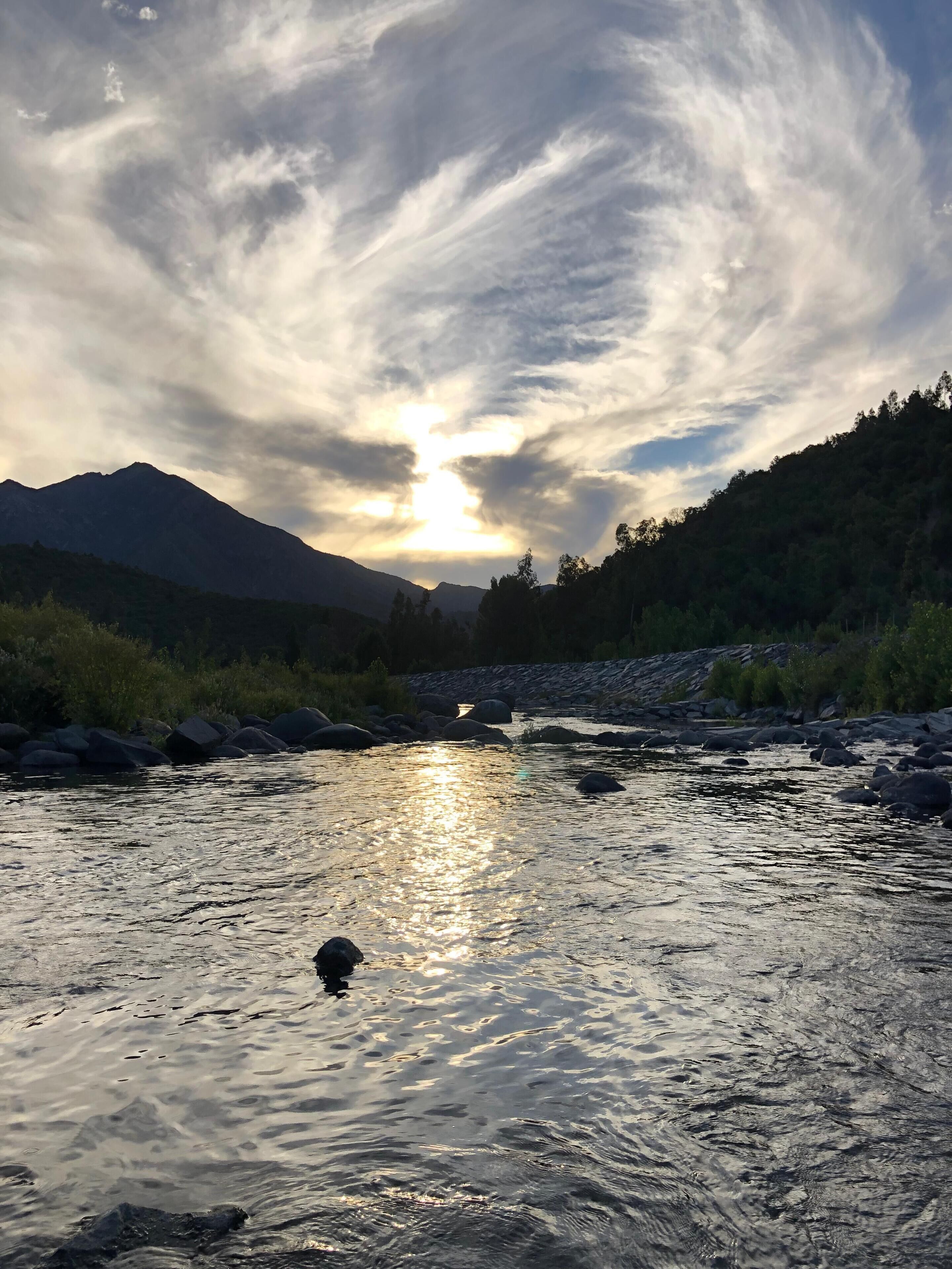 Un río con una montaña al fondo y un cielo nublado.