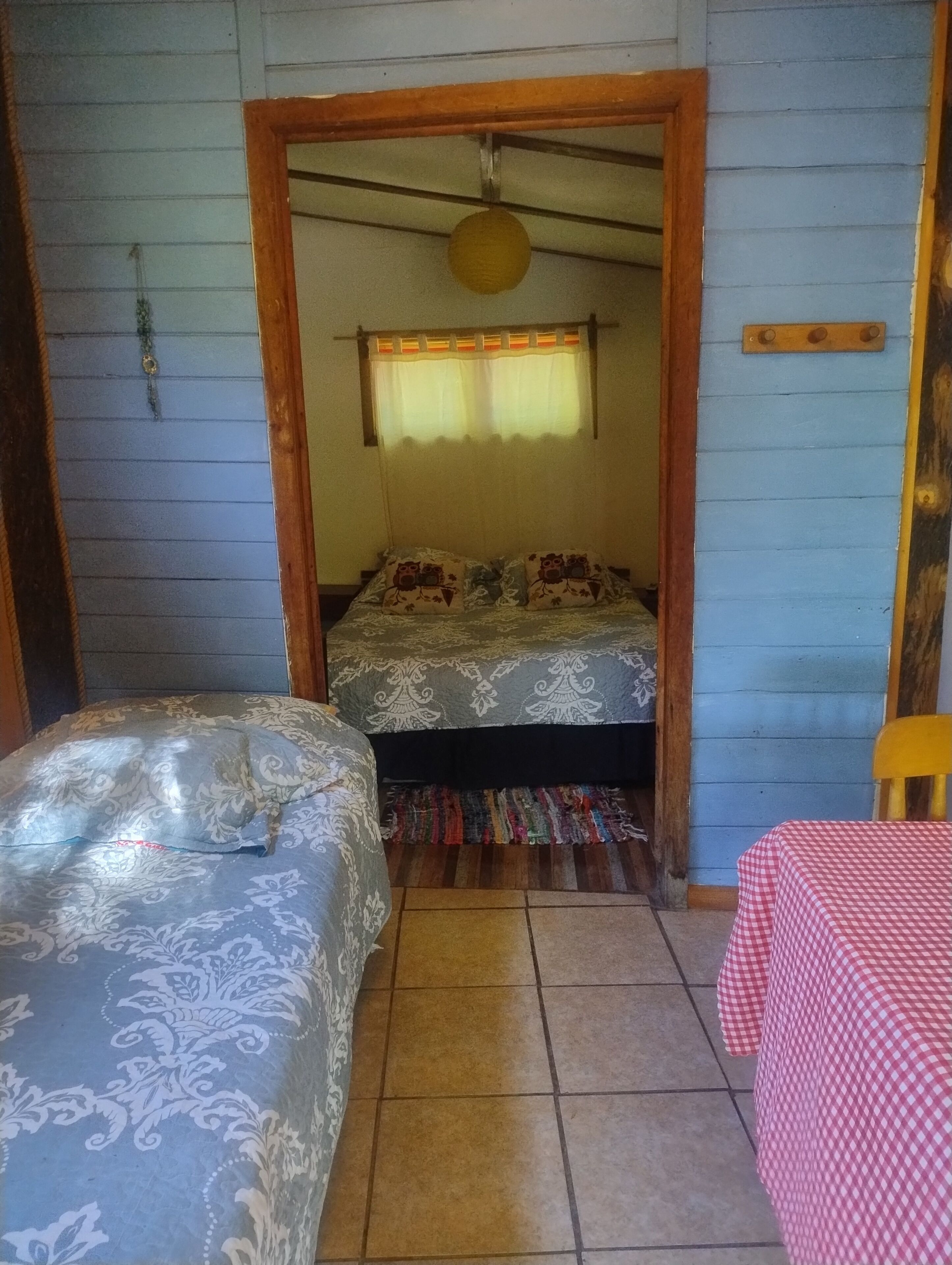 Una habitación con dos camas, una mesita pequeña y un tapete colorido.