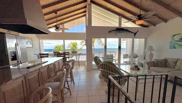 A spacious kitchen with a large island, dining area with chairs, a sofa, and a view of the ocean. - Amazing Ocean Front Views 3 bedroom / bath Villa. Wake up to a Sunrise (Key Largo)