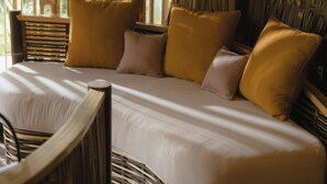 A bed with a curved headboard, a wooden chair, and a woven floor. - The Kul Kul Farm (Abiansemal)