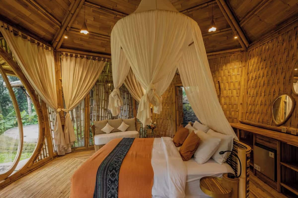 A room with a large bed, two smaller beds, and a canopy bed. There are curtains and a mirror on the wall.