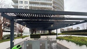 An outdoor area with a covered seating area, a trash bin, and a water feature.