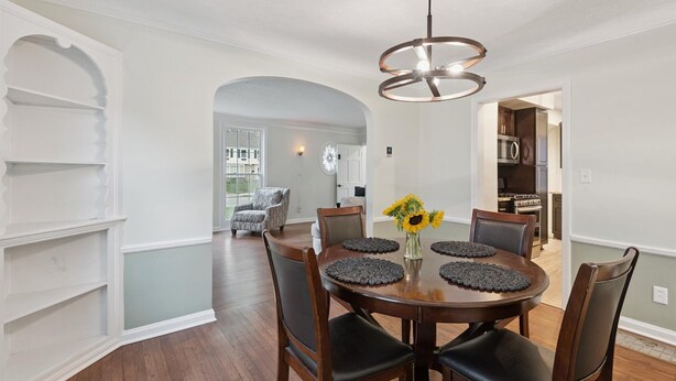A dining area with a round table, dark chairs, and a modern pendant light.