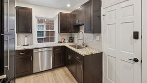 A modern kitchen with dark cabinetry, stainless steel appliances, and a granite countertop.