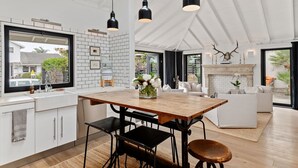 Une cuisine moderne avec une table en bois, des chaises noires et des luminaires suspendus.