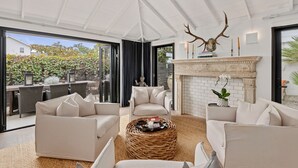 Un salon moderne avec une cheminée, des canapés blancs et une grande fenêtre donnant sur un jardin.