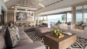 A modern living room with a large sectional sofa, a coffee table with fruits, and a view of the sea. - Element of 8 at Cape Laem Sor Estate by Elite Havens (Surat Thani)