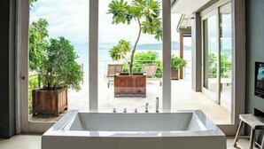 A modern bathroom with a large bathtub, a view of a balcony with potted plants and a chair, and a large window. - Element of 8 at Cape Laem Sor Estate by Elite Havens (Surat Thani)